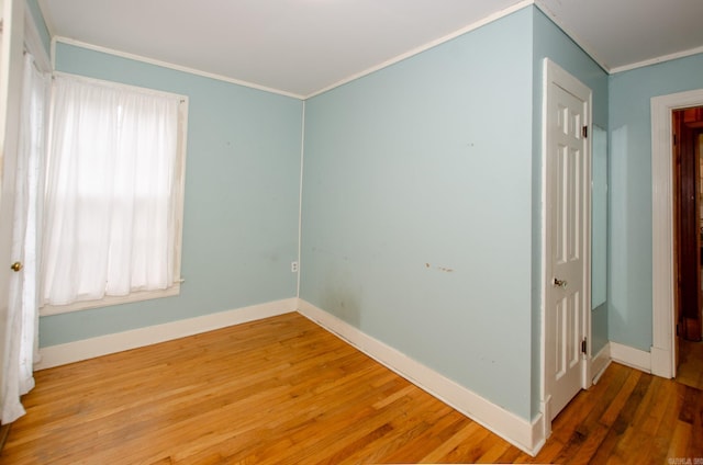 unfurnished room featuring baseboards, wood finished floors, and crown molding