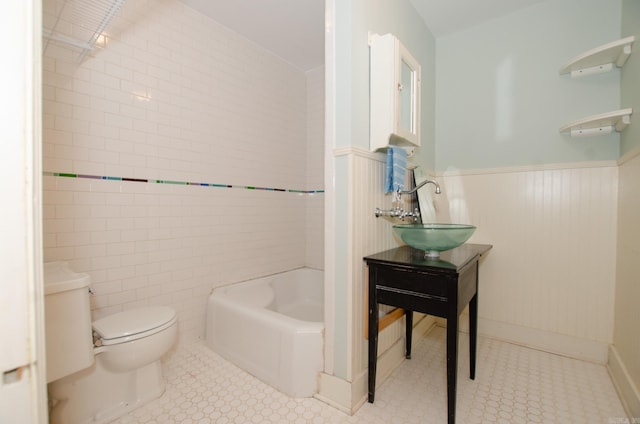 full bathroom featuring a wainscoted wall, tile walls, shower / bathing tub combination, toilet, and a sink