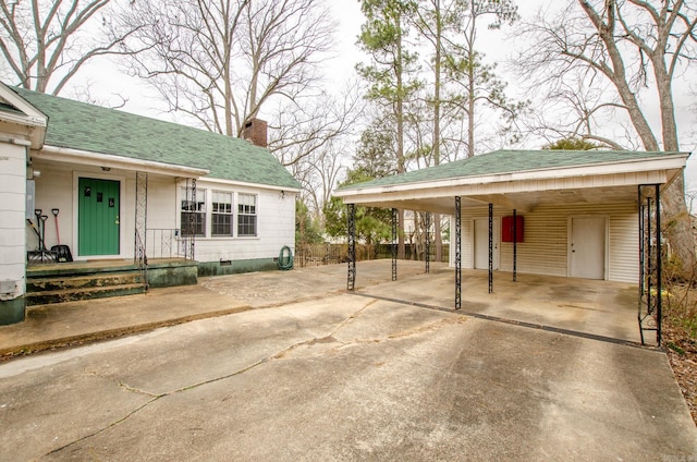 exterior space with concrete driveway, crawl space, a chimney, and roof with shingles