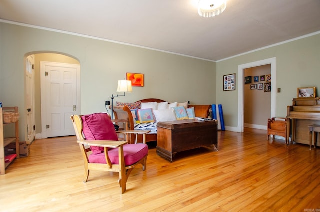 bedroom with light wood finished floors, baseboards, ornamental molding, and arched walkways