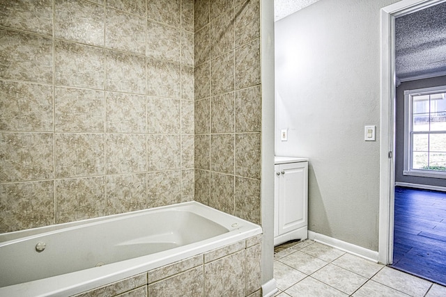 bathroom featuring a textured wall, a textured ceiling, tile patterned flooring, baseboards, and a bath