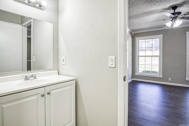 bathroom with ceiling fan, wood finished floors, a textured ceiling, vanity, and crown molding