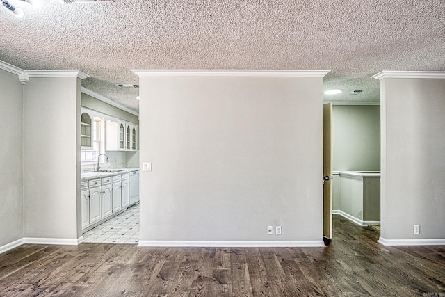 empty room featuring a textured ceiling, a sink, baseboards, light wood-style floors, and ornamental molding