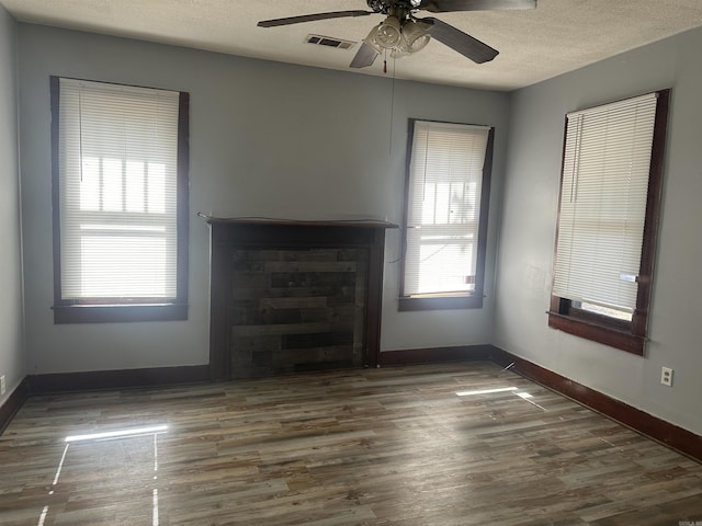 unfurnished living room featuring dark wood finished floors, visible vents, ceiling fan, a textured ceiling, and baseboards