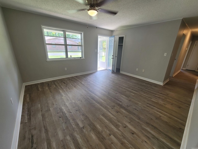 empty room with dark wood-style floors, a ceiling fan, baseboards, and a textured ceiling