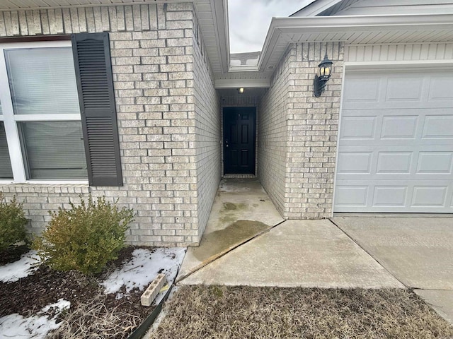 doorway to property featuring a garage and brick siding