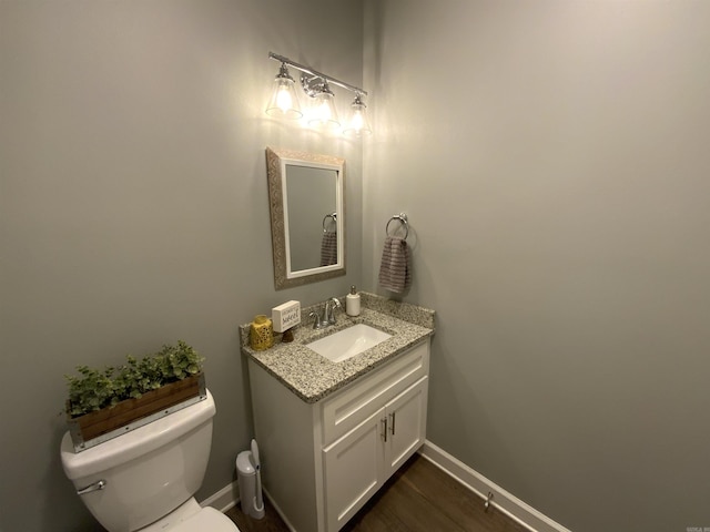 bathroom featuring toilet, baseboards, wood finished floors, and vanity