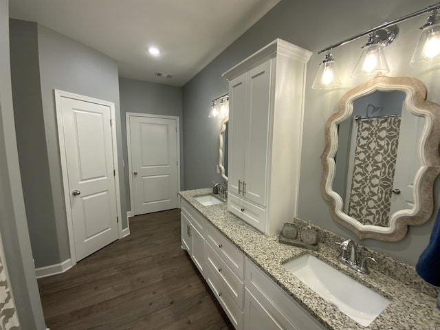 bathroom featuring double vanity, visible vents, a sink, and wood finished floors