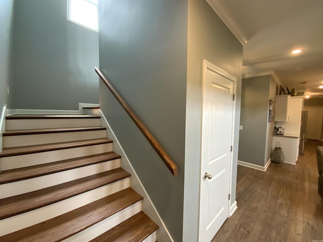 stairs with wood finished floors and recessed lighting