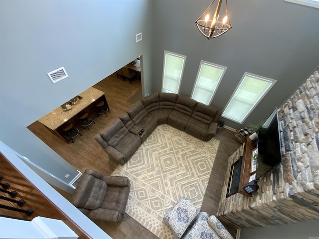 living room featuring a high ceiling, visible vents, a chandelier, and wood finished floors