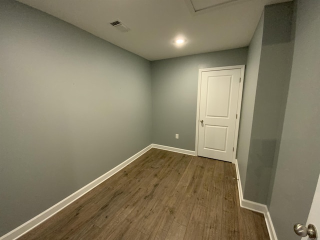 spare room with dark wood-type flooring, visible vents, and baseboards