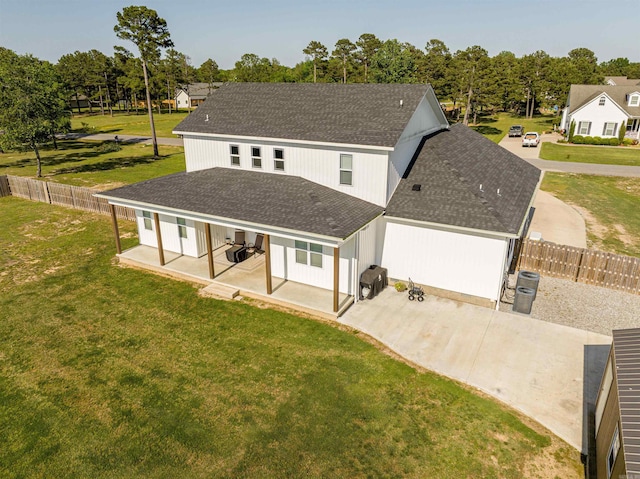 view of front of house featuring roof with shingles, a patio area, a fenced backyard, and a front yard