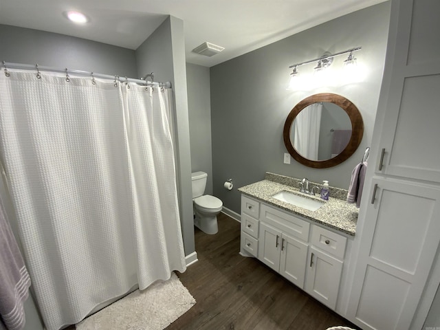 bathroom featuring toilet, wood finished floors, visible vents, vanity, and baseboards