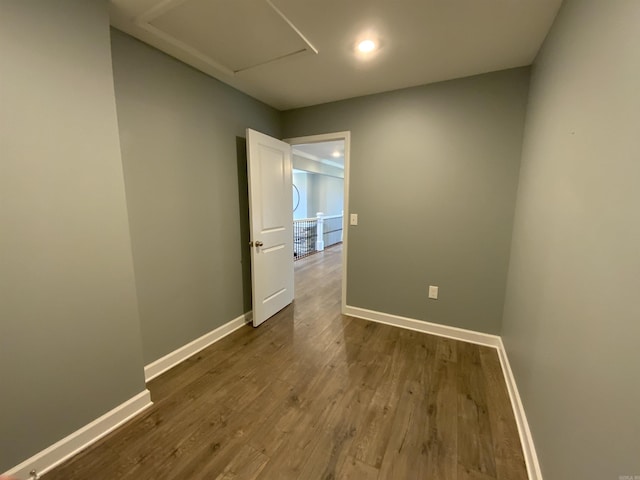 spare room with dark wood-type flooring, attic access, and baseboards