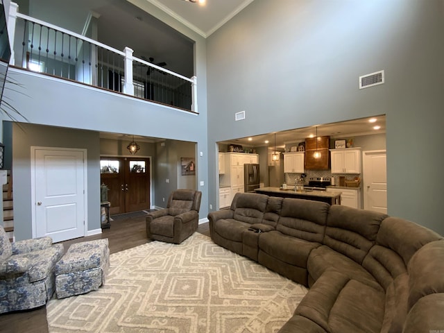 living area with wood finished floors, visible vents, baseboards, stairs, and crown molding