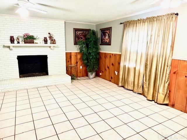 840 S 16th St, Arkadelphia, AR 71923 - unfurnished living room featuring a textured ceiling, wood walls, ornamental molding, wainscoting, and a brick fireplace