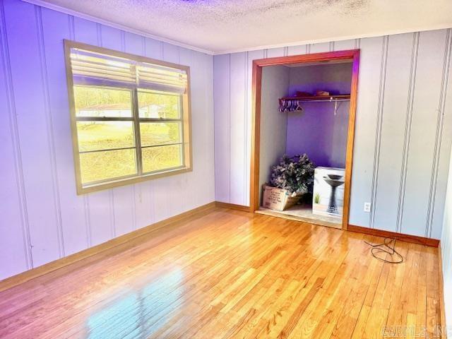 840 S 16th St, Arkadelphia, AR 71923 - unfurnished bedroom featuring light wood-style floors, a closet, a decorative wall, and a textured ceiling