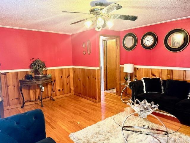 840 S 16th St, Arkadelphia, AR 71923 - living area featuring a wainscoted wall, light wood-style flooring, ceiling fan, ornamental molding, and a textured ceiling