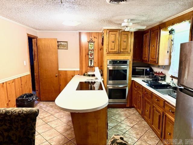 840 S 16th St, Arkadelphia, AR 71923 - kitchen featuring stainless steel appliances, wainscoting, light countertops, and brown cabinetry