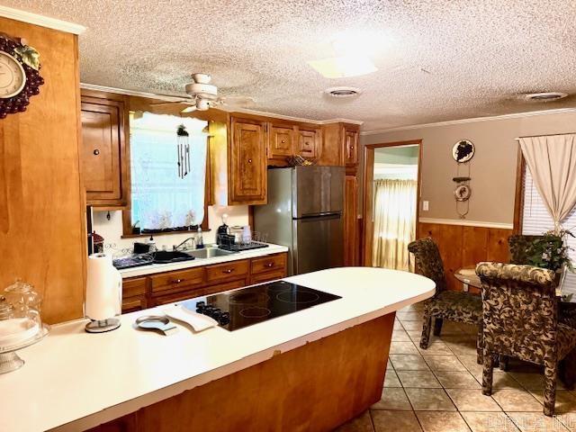 840 S 16th St, Arkadelphia, AR 71923 - kitchen featuring black electric stovetop, light countertops, brown cabinetry, freestanding refrigerator, and wainscoting