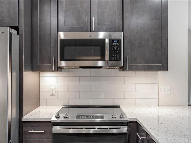 kitchen with stainless steel appliances, tasteful backsplash, dark brown cabinetry, and light stone countertops