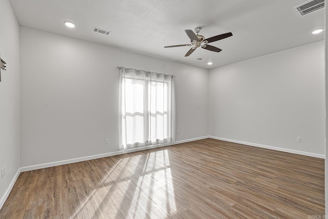 spare room featuring baseboards, visible vents, and wood finished floors