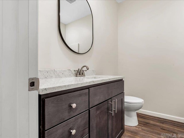 bathroom featuring toilet, wood finished floors, vanity, and baseboards