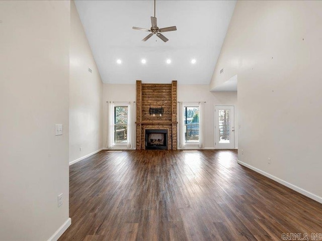 unfurnished living room featuring high vaulted ceiling, a fireplace, dark wood finished floors, and a wealth of natural light