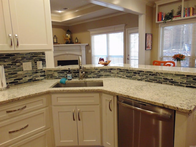 kitchen with a sink, decorative backsplash, dishwasher, a raised ceiling, and crown molding