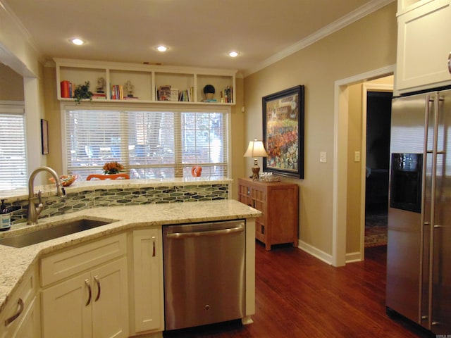 kitchen with light stone counters, stainless steel appliances, a sink, white cabinets, and ornamental molding