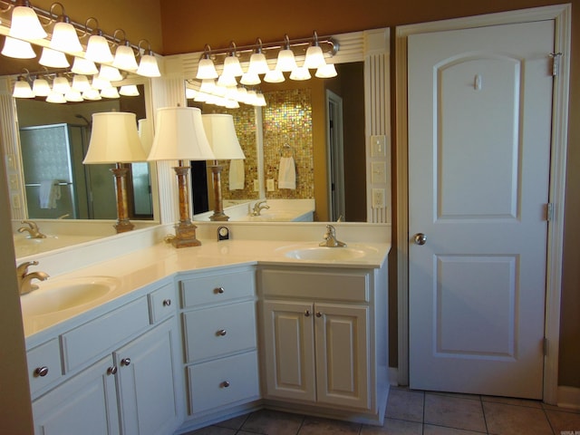 bathroom featuring double vanity, a shower stall, a sink, and tile patterned floors