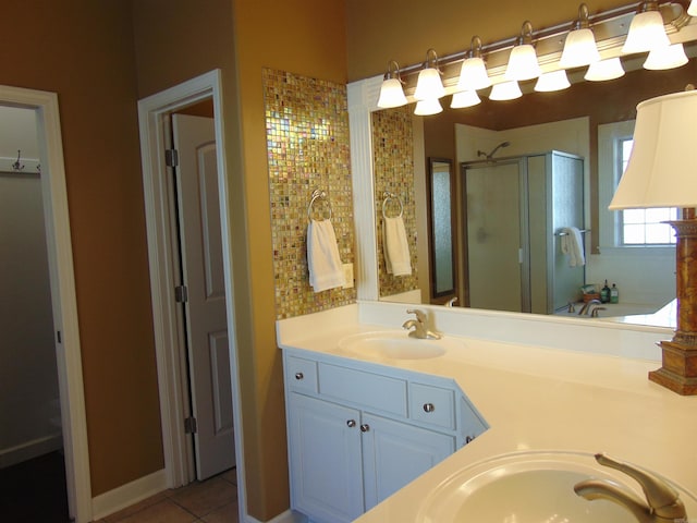 full bath with double vanity, a stall shower, a sink, and tile patterned floors