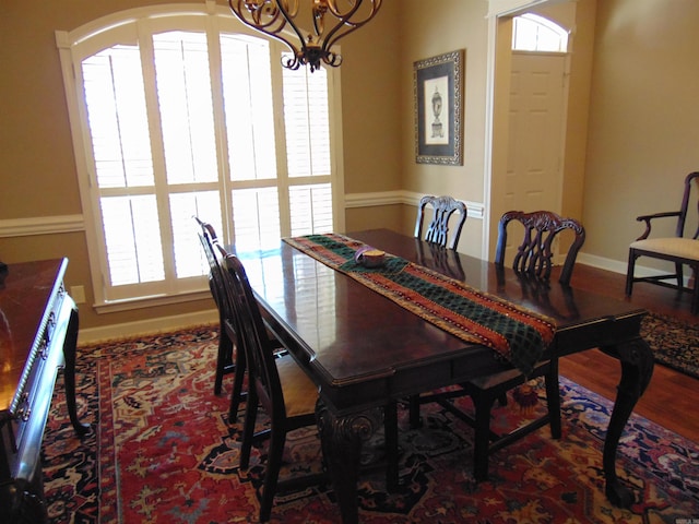 dining room featuring a chandelier, wood finished floors, and baseboards