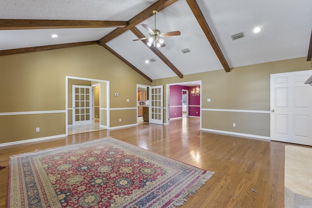 unfurnished living room featuring light wood-style floors, visible vents, beamed ceiling, and ceiling fan with notable chandelier