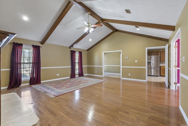 interior space featuring a textured ceiling, lofted ceiling with beams, visible vents, and light wood-style floors