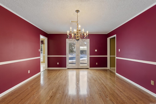 unfurnished room featuring baseboards, ornamental molding, wood finished floors, and an inviting chandelier