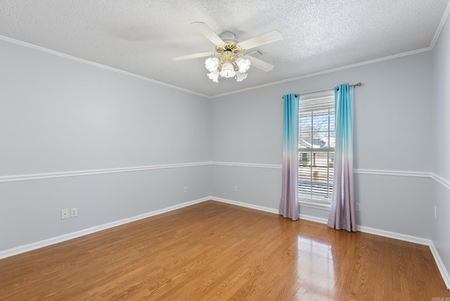 empty room featuring baseboards, a ceiling fan, ornamental molding, wood finished floors, and a textured ceiling