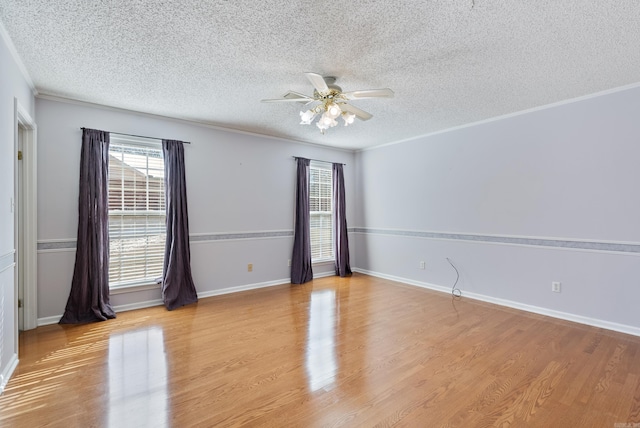 empty room featuring ornamental molding, a ceiling fan, a textured ceiling, light wood-type flooring, and baseboards