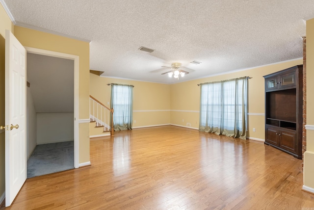 unfurnished living room featuring visible vents, ceiling fan, stairway, ornamental molding, and wood finished floors