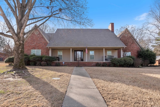 view of front of home with a chimney, a front lawn, a porch, and brick siding