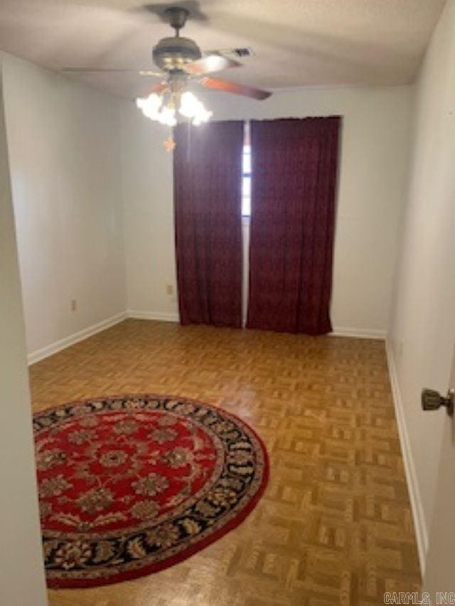 unfurnished room with a ceiling fan and baseboards