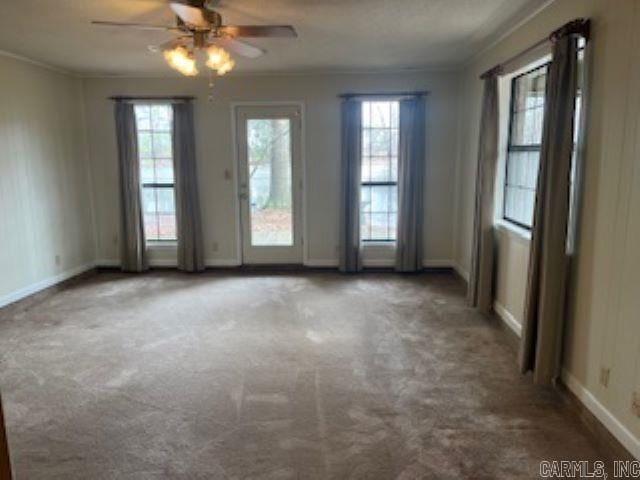 unfurnished room with carpet floors, plenty of natural light, a ceiling fan, and crown molding