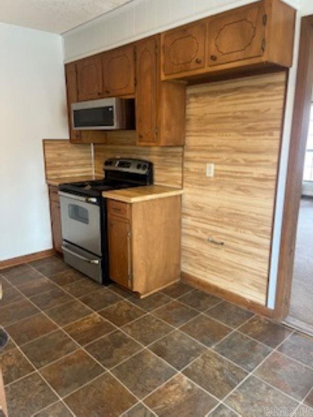 kitchen featuring stainless steel appliances, light countertops, brown cabinets, and baseboards