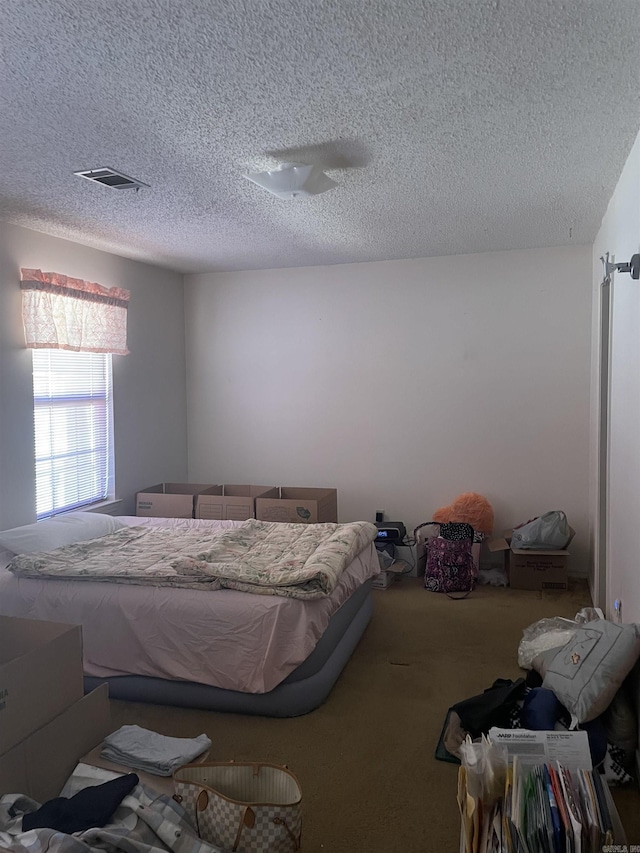 bedroom featuring carpet floors, visible vents, and a textured ceiling