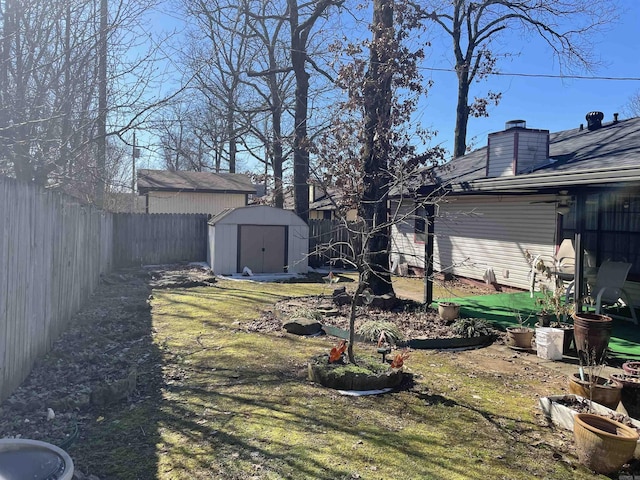 view of yard featuring a shed, a fenced backyard, and an outbuilding