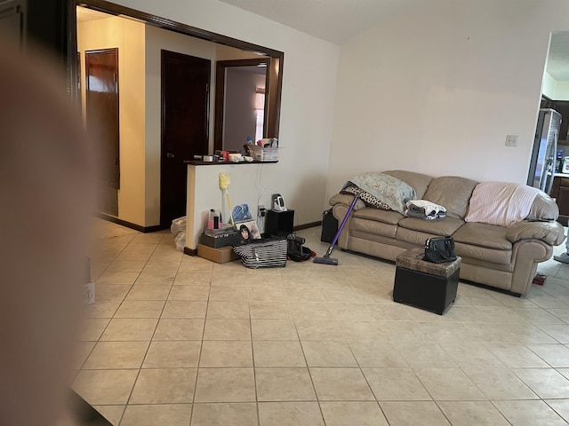 living area with light tile patterned flooring, vaulted ceiling, and baseboards