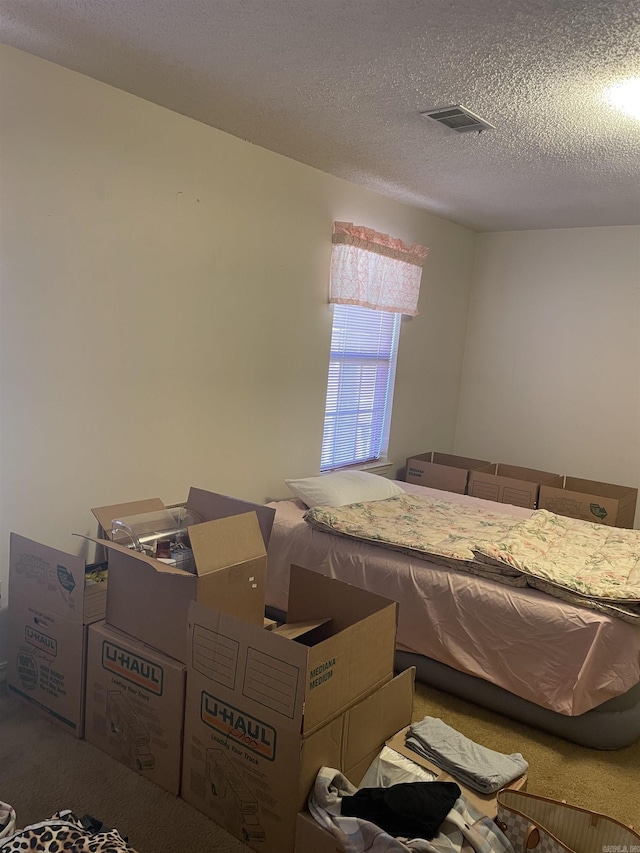 carpeted bedroom featuring visible vents and a textured ceiling