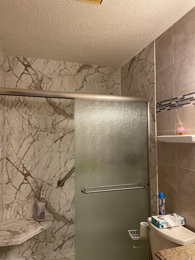 full bathroom with toilet, a shower stall, and a textured ceiling