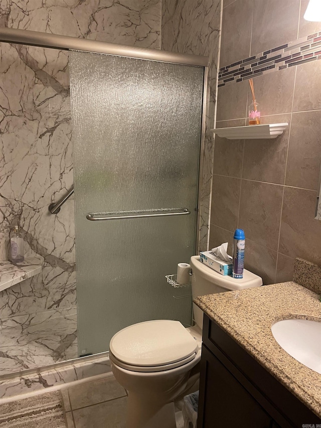 full bathroom featuring tile walls, toilet, a shower stall, and vanity