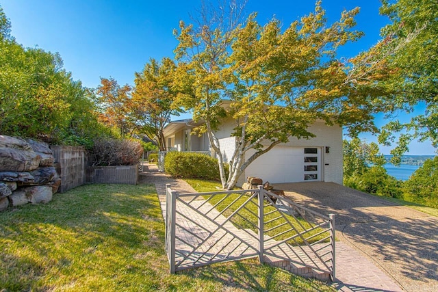 exterior space with a yard, a water view, fence, a garage, and driveway